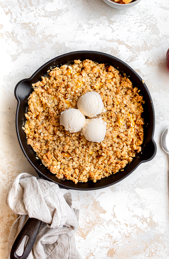 peach crisp with oatmeal topping in a cast iron skillet